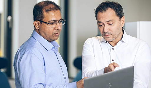 Two men in shirts are looking at a laptop together (Photo)