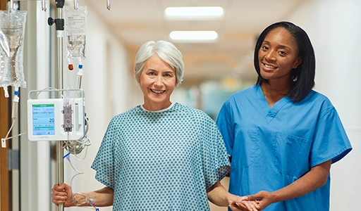 A patient and a hospital employee are standing together and smiling (Photo)