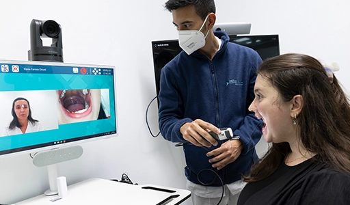 An employee and a patient are examining the inside of the patient’s mouth together using a camera (Photo)