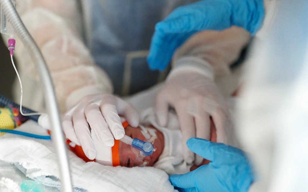 Krankenhauspersonal und Patientin am Krankenhausbett lächeln sich gegenseitig an