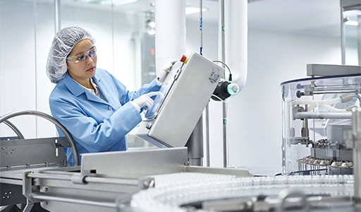 Eine Frau in Arbeitskleidung bedient eine Maschine (Foto)