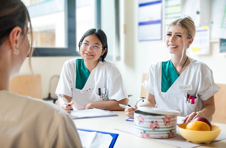 Tres profesionales sanitarios se sientan a la mesa y se comunican sonriendo (foto)