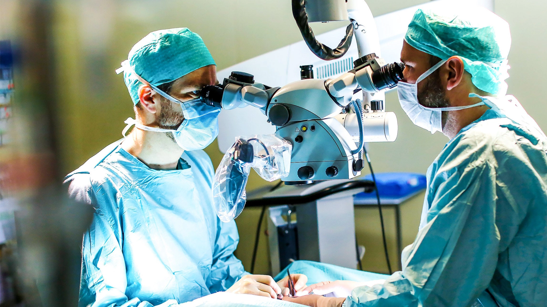 Personal médico observa a través de un microscopio y realiza un procedimiento (foto)