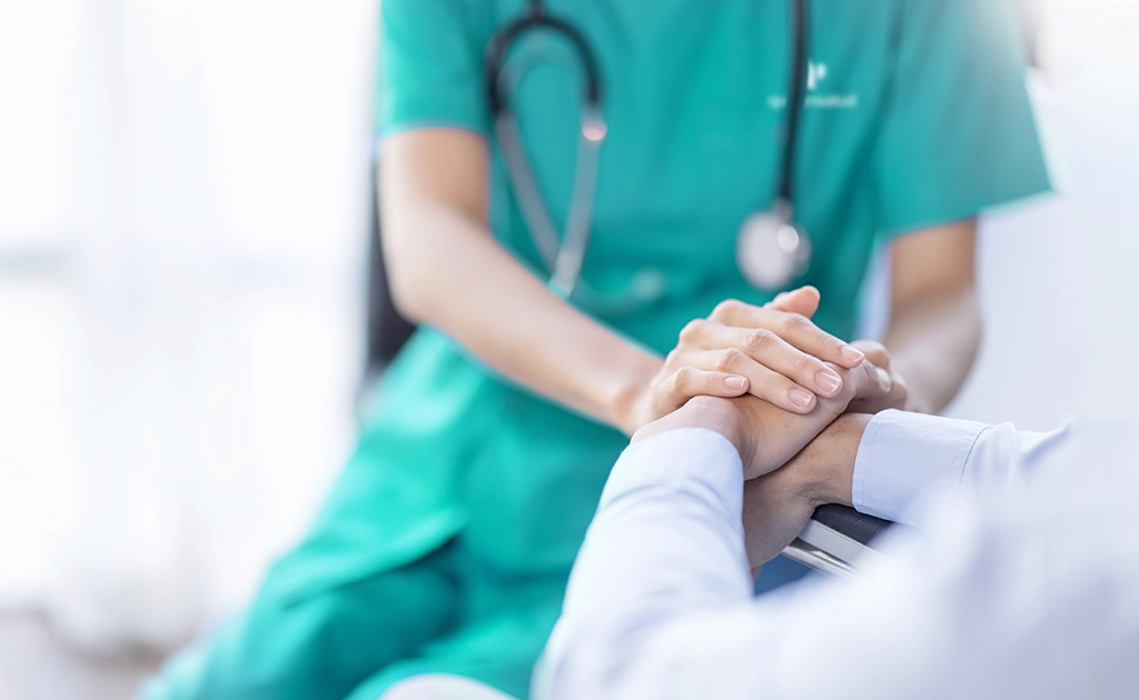 Médico sostiene las manos de una persona de forma reconfortante (foto)