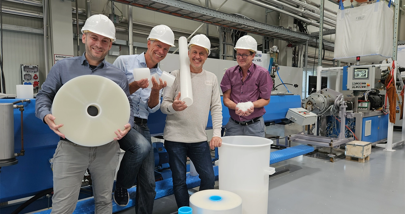 Four people wearing helmets and production clothing smile at the camera (photo)